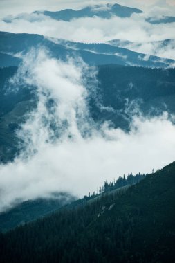 Bulutlarda mavi dağlar olan manzaralı bir yer.