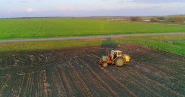 Tarımsal alana kimyasal püskürten püskürtücü yüklü bir traktör. Hava görünümü.