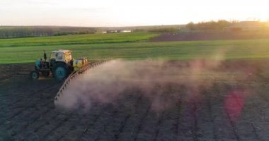 Tarımsal alana kimyasal püskürten püskürtücü yüklü bir traktör. Hava görünümü.