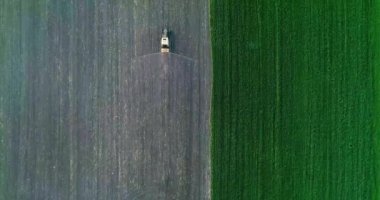 Tarımsal alana kimyasal püskürten püskürtücü yüklü bir traktör. Hava görünümü.