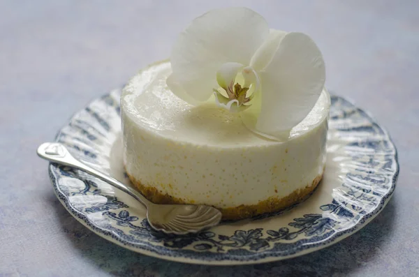 No hornear tarta de queso en un plato azul con orquídea —  Fotos de Stock