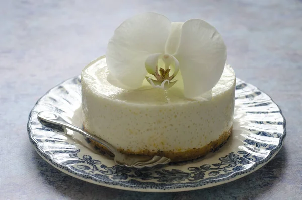 No hornear tarta de queso en un plato azul con orquídea —  Fotos de Stock