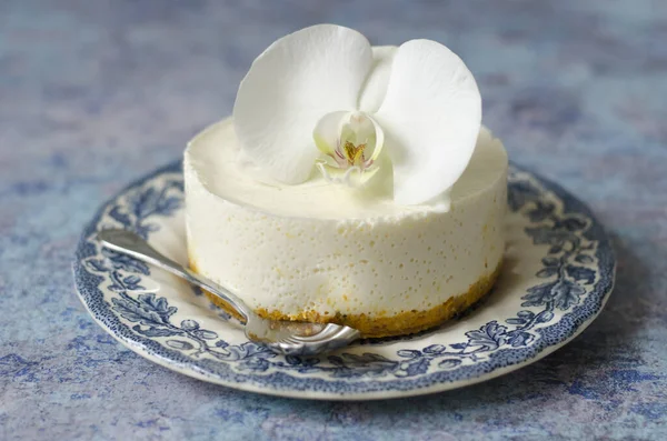 No hornear tarta de queso en un plato azul con orquídea —  Fotos de Stock