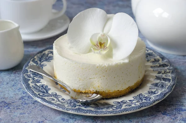 No hornear tarta de queso en un plato azul con orquídea —  Fotos de Stock