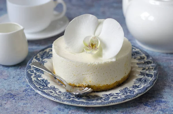 No hornear tarta de queso en un plato azul con orquídea —  Fotos de Stock