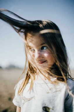Dışarıdaki kameraya bakan uzun saçlı şirin bir kızın portresi. 