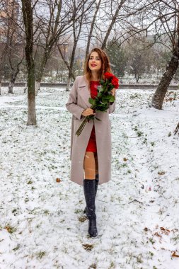 Kız elinde bir buket kırmızı gül tutuyor..