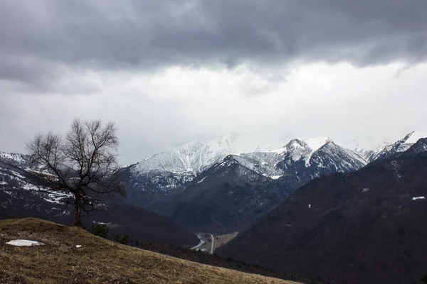 Snow-capped mountains in the fog. Caucasian ridge at the beginning of winter. The first snow in the mountains of Russia.