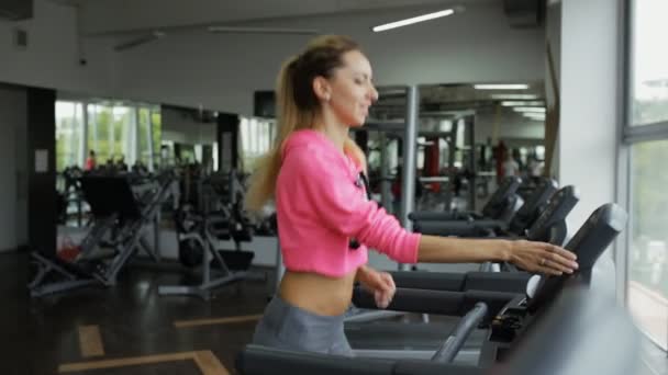 Доросла спортивна жінка біжить на біговій доріжці в спортзалі — стокове відео