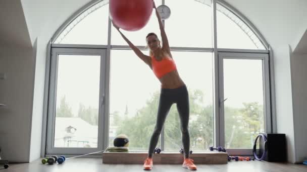 Mulher fazendo um exercício de alongamento lateral usando fitball no estúdio de fitness — Vídeo de Stock