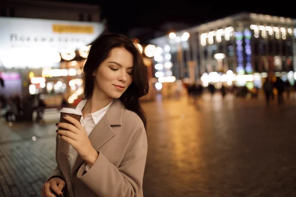 Vrouw lopen in nacht stad en warme aroma koffie drinken — Stockfoto