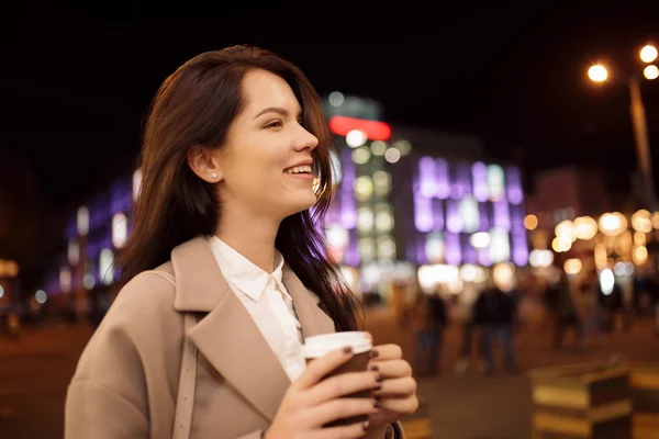 Mulher na cidade da noite mantendo xícara de café e apreciando o aroma — Fotografia de Stock