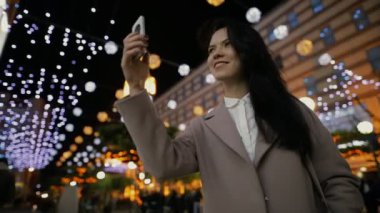Gece şehirde yürüyüş ve akıllı telefon ışıklı Caddesi'ne fotoğrafçılık kadın