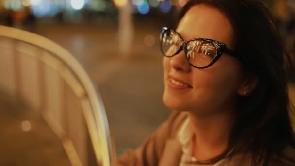 Momento romántico en la ciudad nocturna. Mujer buscando carrusel iluminado . — Vídeo de stock