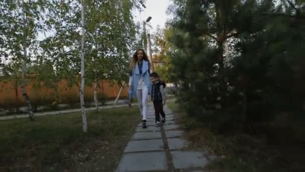 Mor med son gå mellan tallarna på höstkväll — Stockvideo