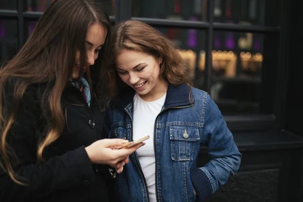 Açık havada kahve içme ve smartphone City bakarak iki kadın portresi