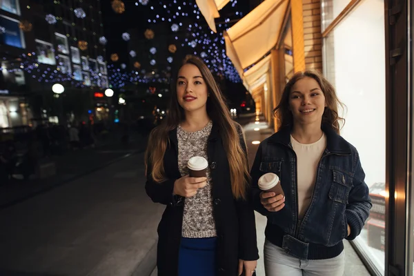 Zwei stylische Freundinnen, die nachts in der City Avenue spazieren gehen — Stockfoto