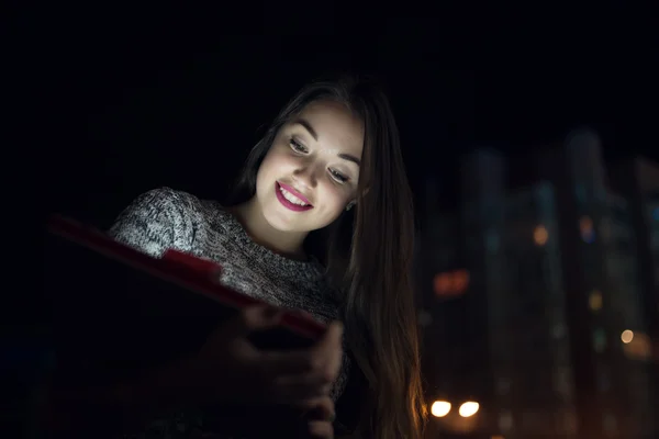 Young women look down to digital tablet in balcony at night city — Stock Photo, Image