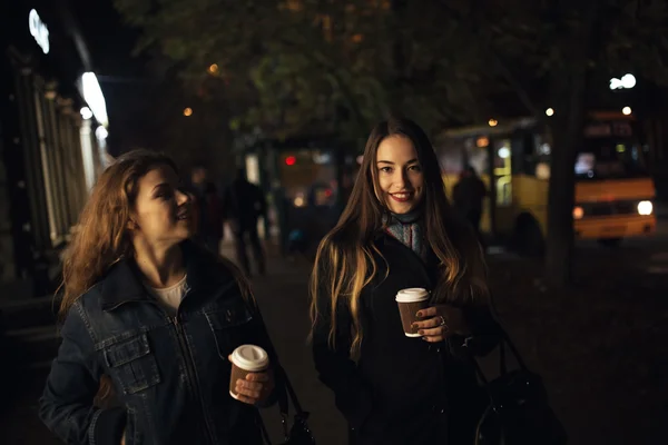 Dos novias a la moda caminando por la avenida de la ciudad por la noche —  Fotos de Stock