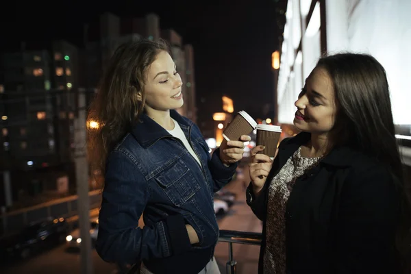 Dva přátelé mladá žena si vychutnat kávu v balkon v noci — Stock fotografie