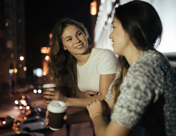 Twee jonge vrouw vrienden spreken in balkon bij nacht — Stockfoto