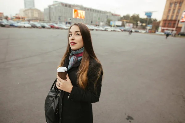 Žena v městě, ona drží šálek kávy — Stock fotografie