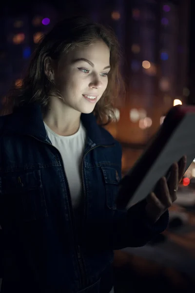 Young women look down to digital tablet in balcony at night city — Stock Photo, Image
