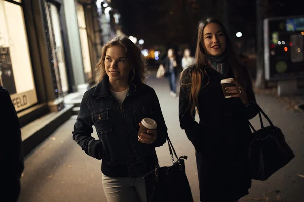 Dos novias a la moda caminando por la avenida de la ciudad por la noche —  Fotos de Stock