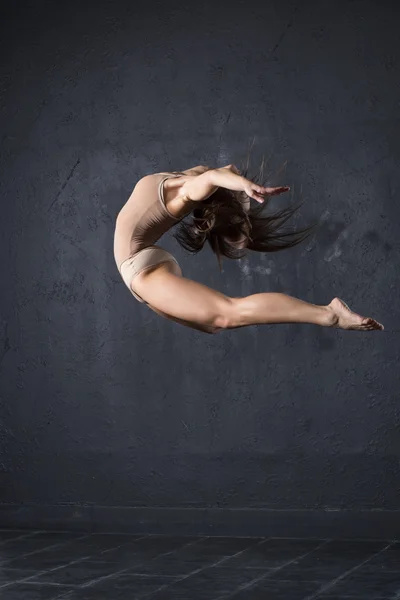 Young professional dancer jumping against textured wall background