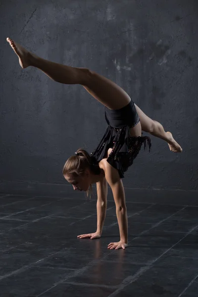 Woman dancer make handstand in dark studio — Stock Photo, Image