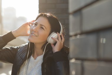 Kadın beyaz kulaklık ile şehir içinde müzik dinlemek