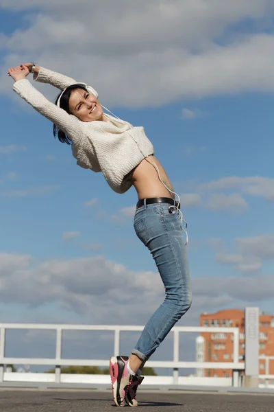 Woman listen music and jump at city background — ストック写真