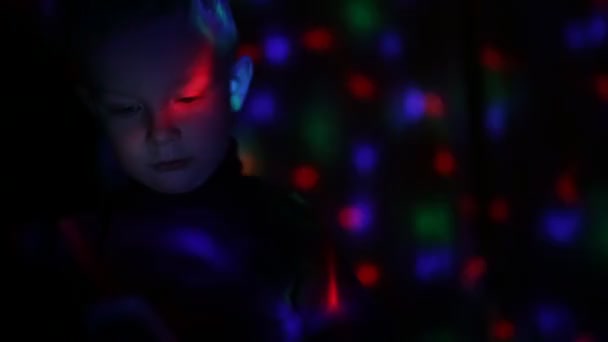 Disco light lamp on a little boy, he using smartphone — Stock video