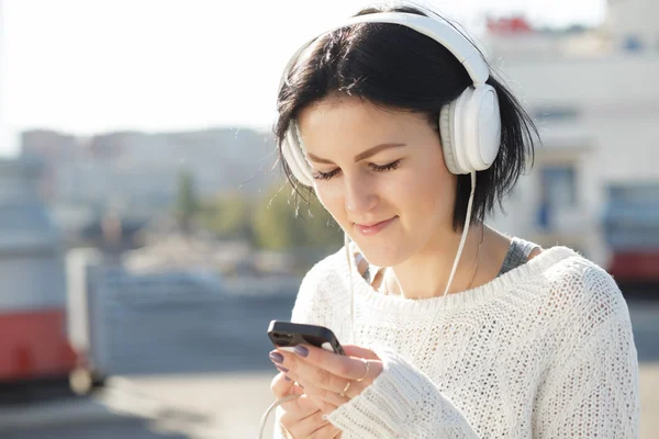 Frau in weißen Kopfhörern hört Musik im Freien — Stockfoto