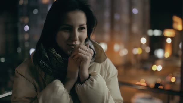 Mujer calentando las manos en una ciudad en la fría noche de invierno — Vídeos de Stock