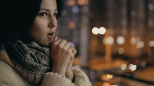 Vrouw opwarming van de aarde handen in een stad op koude winternacht — Stockvideo