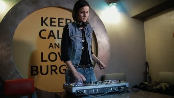 Жінка DJ Twak різні елементи управління треком на палубі діджея в нічному клубі — стокове відео