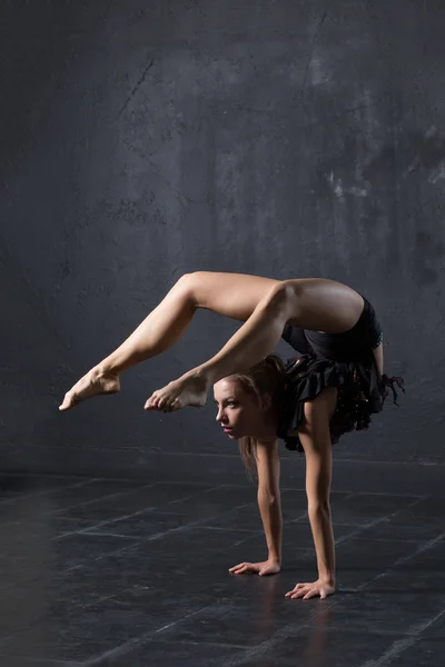 Woman dancer make handstand in dark studio — Stock Photo, Image