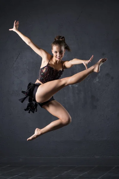 Menina bonita dançando no fundo de parede texturizado cinza — Fotografia de Stock