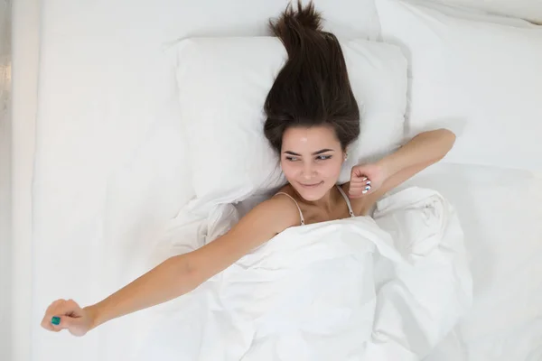 Woman lying in bed and stretching arms in the morning — Stock Photo, Image