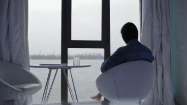 Penceresine bakarak ve rahat bir sandalye üzerinde rahatlatıcı bir kadın