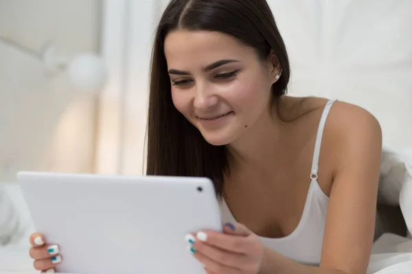 Moderne Frau liegt morgens mit Tablet-PC im Bett — Stockfoto