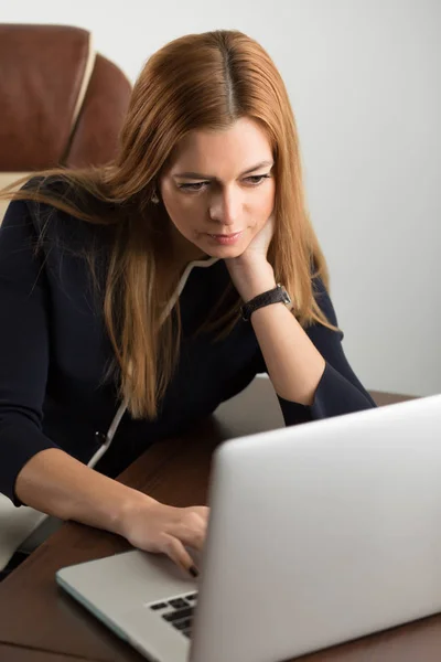 Attraente donna adulta seduta alla sua postazione di lavoro in ufficio — Foto Stock