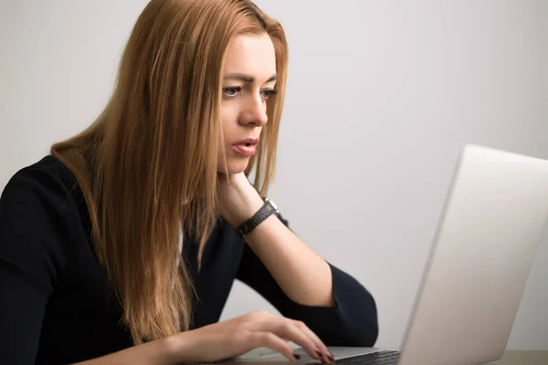 Empresaria sentada en su puesto de trabajo en la oficina y trabajando por cuaderno —  Fotos de Stock