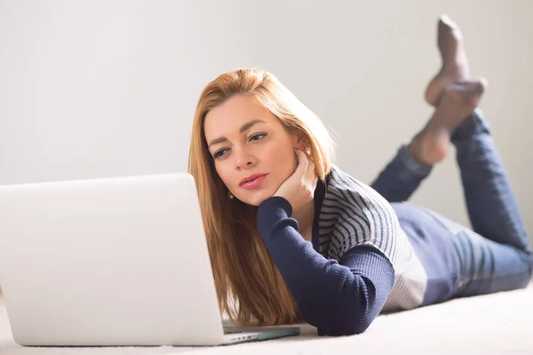 Bella donna adulta sdraiata sul pavimento a casa e utilizzando il computer portatile — Foto Stock