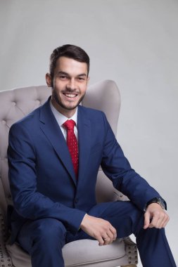Koltuk, gri arka plan üzerinde oturan beyaz işadamı portresi