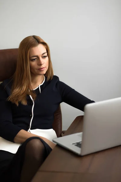 Mulher sentada em seu posto de trabalho no escritório e trabalhando por caderno — Fotografia de Stock