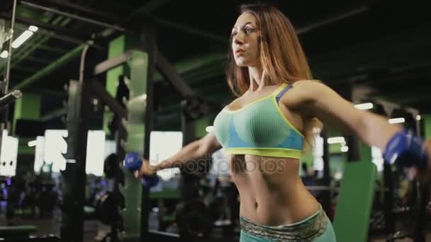 Сильная женщина делает упражнения в спортзале. Она поднимает гантели . — стоковое видео