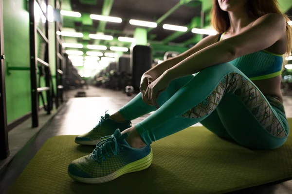 Mujer sentada en el gimnasio y descansando antes del ejercicio - tiro recortado —  Fotos de Stock