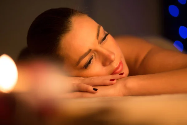 Mooie vrouw liegen en ontspannen na spa massage door kaarslicht — Stockfoto